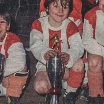 Young soccer player holding silver trophy with golden figure on top