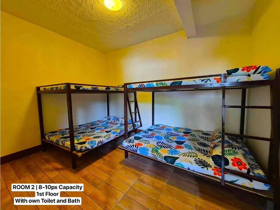 Two wooden bunk beds with floral sheets in a yellow-walled room with tiled floor