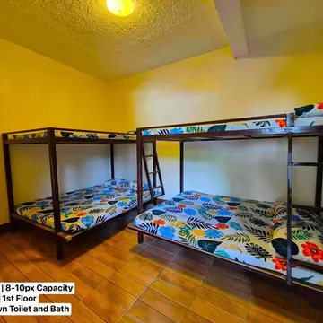 Two wooden bunk beds with floral sheets in a yellow-walled room with tiled floor