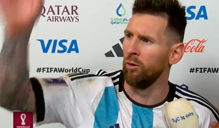 Lionel Messi in Argentina jersey at FIFA World Cup press conference with sponsor logos behind him