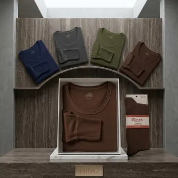 Four folded t-shirts and a pair of socks on a wooden shelf with marble base and concrete walls