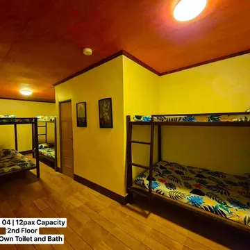 Dorm room with wooden floors and ceilings featuring multiple bunk beds with tropical patterned bedding