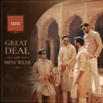 Four men in beige traditional clothing posing under a stone archway
