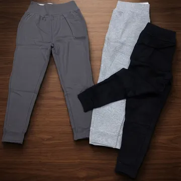 Three pairs of children's joggers in gray black and heather gray on a wooden surface