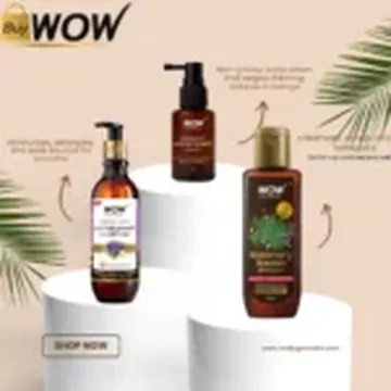 Three WOW hair care bottles on white pedestals with palm leaves and beige background
