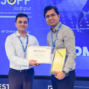 Two men holding an award certificate and trophy at a medical conference event