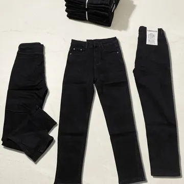 Black denim jeans arranged on a marble surface including folded and laid out styles with visible labels