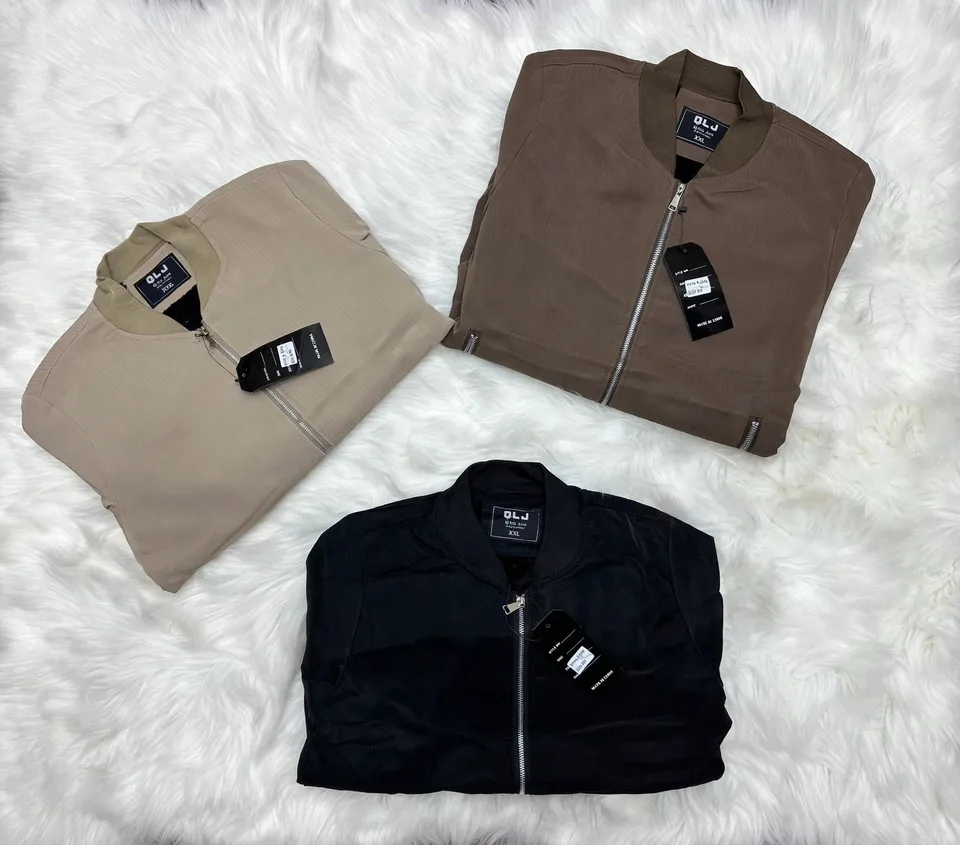 Three folded DLJ bomber jackets in beige brown and black on white faux fur