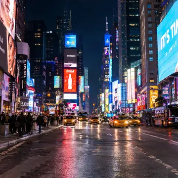 Times Square at night with bright billboards taxis and pedestrians on wet streets