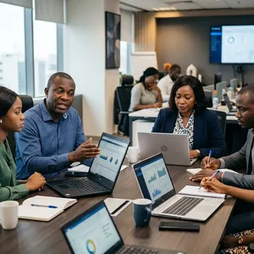 Diverse team reviewing data charts on laptops during a business meeting in a modern office