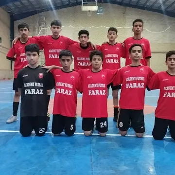 Youth futsal team in red and black uniforms posing on blue indoor court