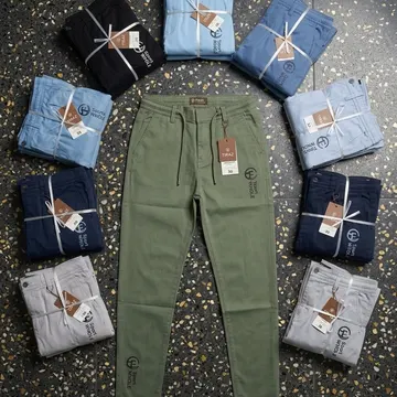 Eight folded colored pants arranged around a single olive green pair on a terrazzo floor