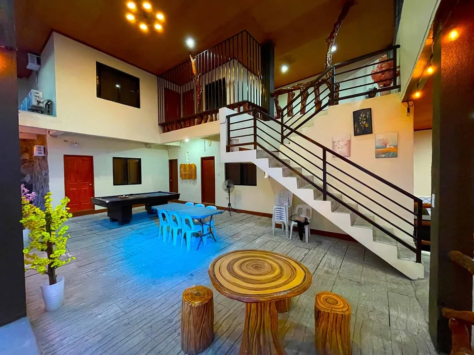 Indoor recreational area with pool table blue chairs wooden table and staircase
