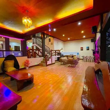 A warmly lit indoor lounge with wooden floors glowing under colorful disco lights and eclectic furniture