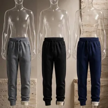 Three mannequins wearing gray black and navy sweatpants in a stone-walled room