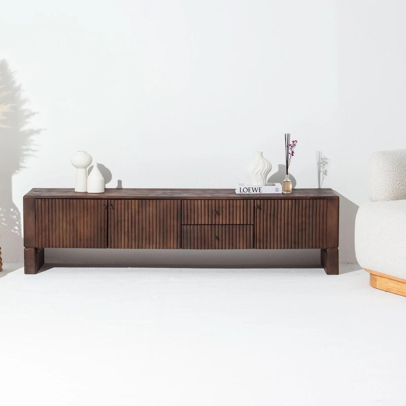 Dark wood console with white vases and book against white wall