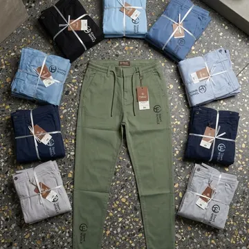 Eight folded bundles of branded pants in blue and gray surround a single olive green pair on a speckled terrazzo floor