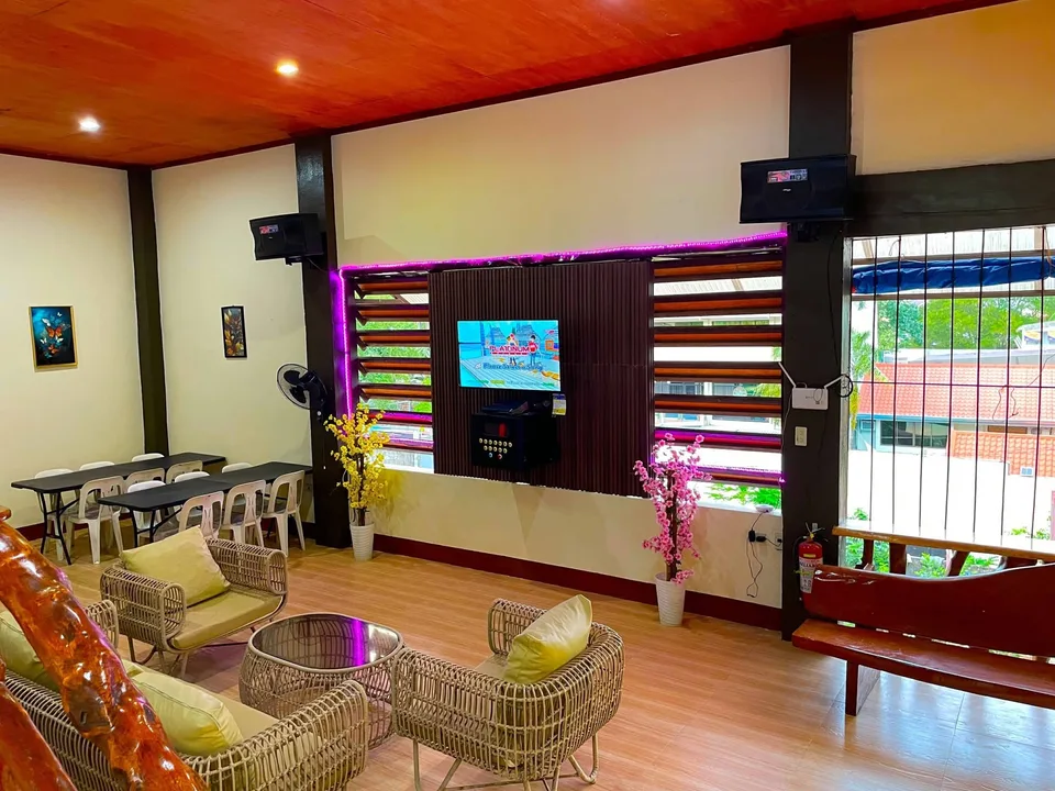 Cozy lounge with wicker chairs yellow cushions and purple neon lights around a karaoke screen