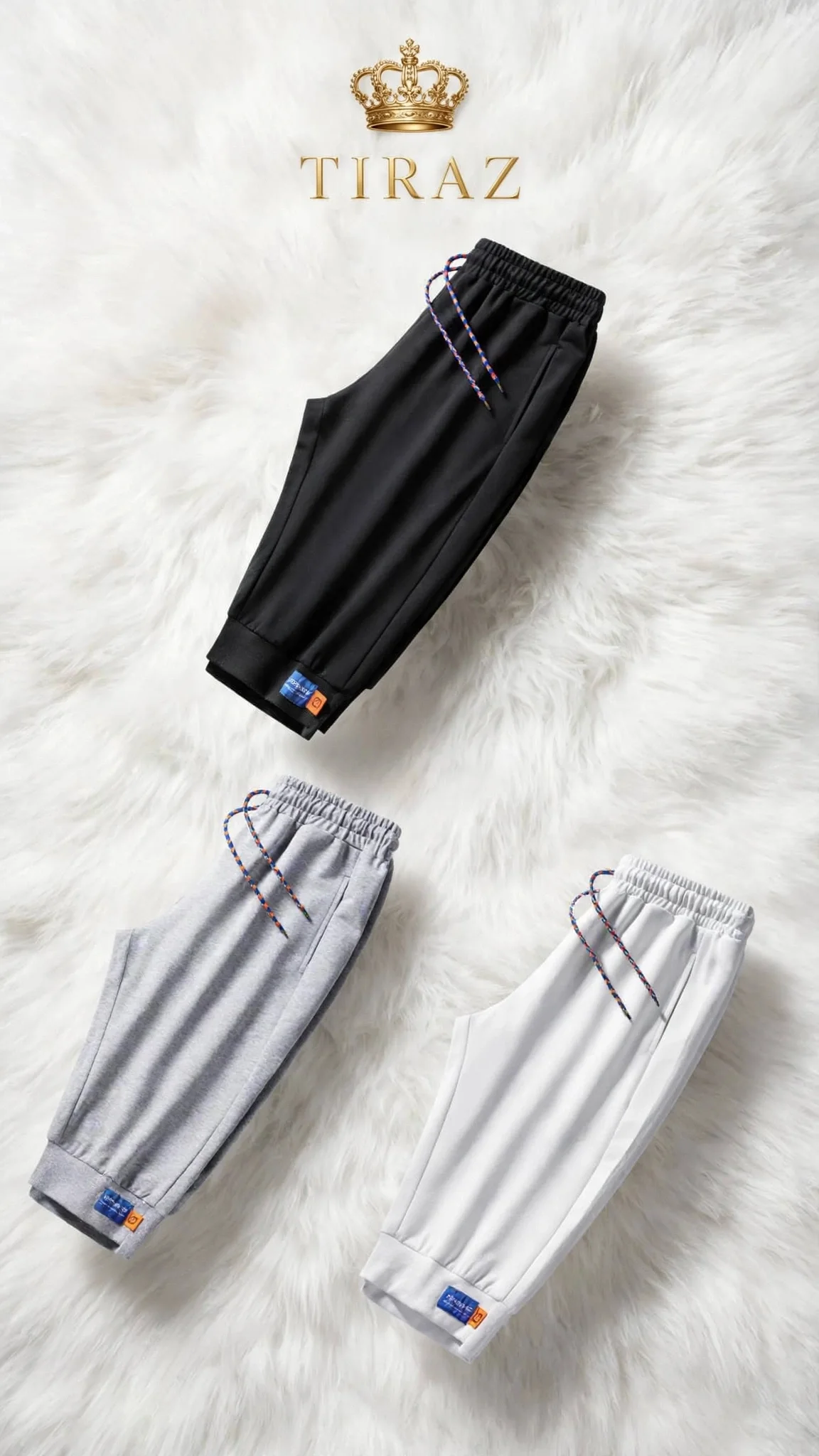 Three colorway joggers with colorful drawstrings on a fluffy white rug under a crown logo