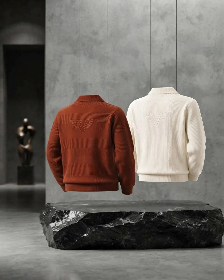 Two ribbed knit sweaters in rust and cream hang suspended above a black marble slab against a gray concrete wall