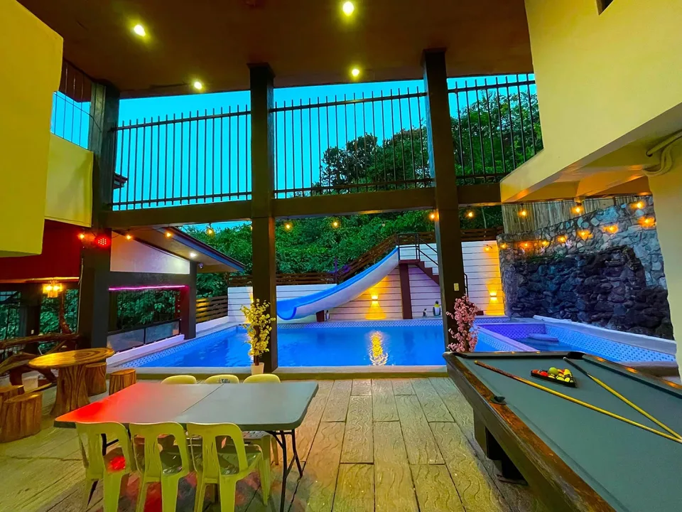 Indoor pool with slide and pool table under evening lights