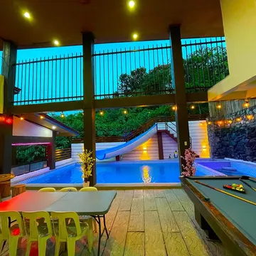Indoor pool with slide and pool table under evening lights