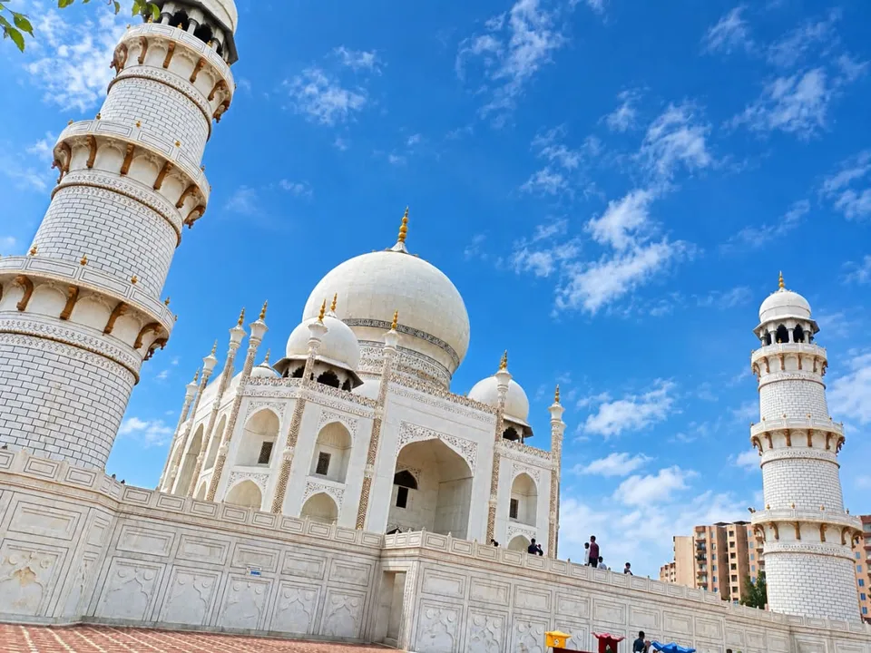 White marble mosque with domes and minarets under a bright blue sky with clouds